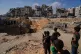 Palestinians watch as Egyptian machinery and workers search for the bodies of hostages in Hamad City, Khan Younis, in the southern Gaza Strip, Tuesday, Oct. 28, 2025
