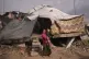 A woman holds a child as they stand in front of their tent in a makeshift camp for displaced Palestinians set up in an area in Gaza City, Monday, Dec. 29, 2025