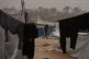 A Palestinian youth walks past tents in a makeshift camp for displaced people during a dust storm in Zawaida, in the central Gaza Strip, February 14, 2026