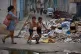 Children run past a pile of trash accumulated on a street during a blackout in Havana, Cuba, July 6, 2026
