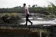 A man walks through a land devastated by an oil spill in Ogo