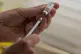 A pharmacist fills a syringe from a vial of the Janssen, Joh