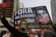 A woman takes a selfie backdropped by a banner depicting Bra