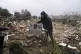 A Palestinian man carries family photos at the ruins of a ho
