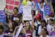 A woman holds a sign that reads in Portuguese 