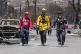 Members of a search-and-rescue team walk along a street, Sat