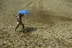 A villager holding umbrella to protect himself from sun, wal
