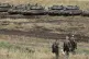 Israeli soldiers walk past tanks in the Israeli-occupied Gol