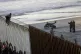 A Central American migrant sits on top of the border structu